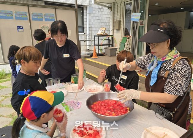 '우리마을 은빛 놀이터’프로그램에 참여한 어르신이 아이들에게 수박화채를 나눠주고 있다.