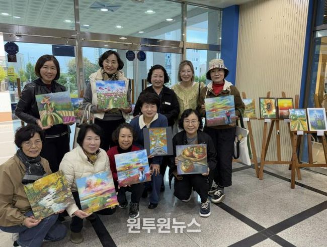 힐링아트(오일파스텔) 전시회’ 현장에서 사천시복지청소년재단 경영본부장(변은진), 강사(박홍은), 회원들이 전시 성료를 기념하며 단체사진을 촬영하고 있다.