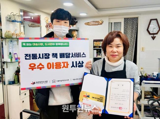 대송시장 헤어세상 심영미 사장이 동부도서관이 주관한 '전통시장 책 배달 프로그램' 우수이용자상을 받고 기념사진을 찍고있다