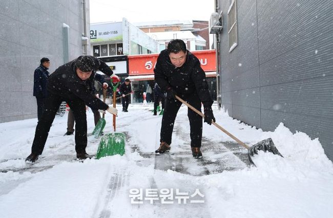 김산 군수와 공무원들이 무안읍 시가지에서 제설 작업을 하고 있다